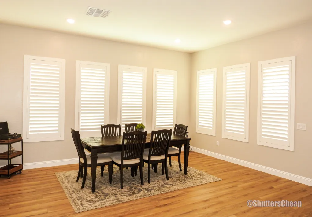 Dining room with tall shutters and designer chandelier